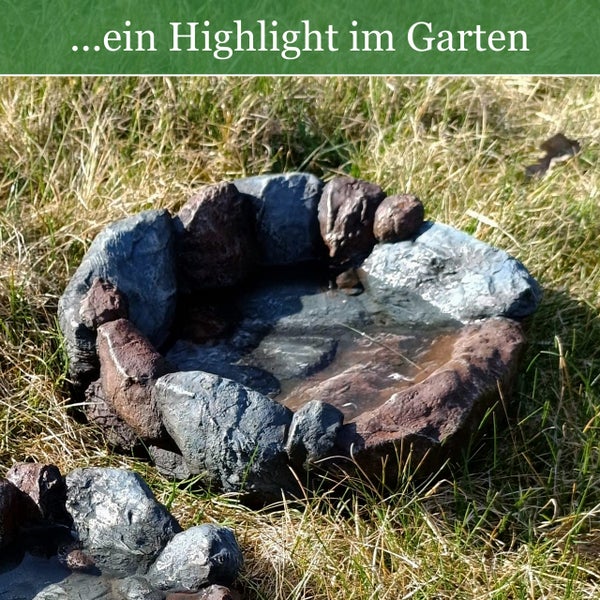 Wasserbecken in Natursteinoptik für den Garten im Gras stehend.