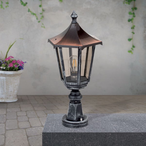 Klassische Außenleuchte im Laternen-Design mit kupferfarbenem Dach und LED-Leuchtmittel auf einem Steinsockel im Gartenbereich.