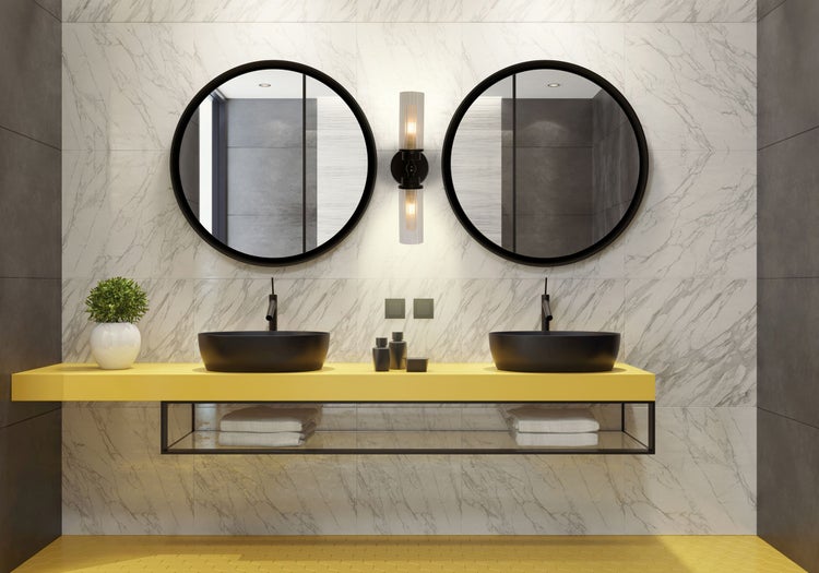 Helles Badezimmer mit Doppelwaschbecken, runden Spiegeln und gelber Ablagefläche.