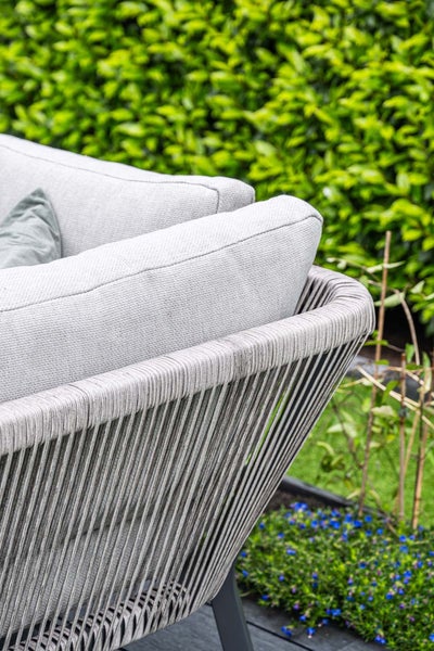 Detailansicht eines Gartenstuhls mit moderner Seilbespannung und dicken Polsterkissen im Garten.