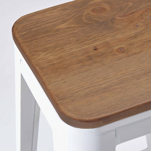 Detailansicht eines Hockers mit einer Sitzfläche aus Holz und einem weißen Metallgestell.