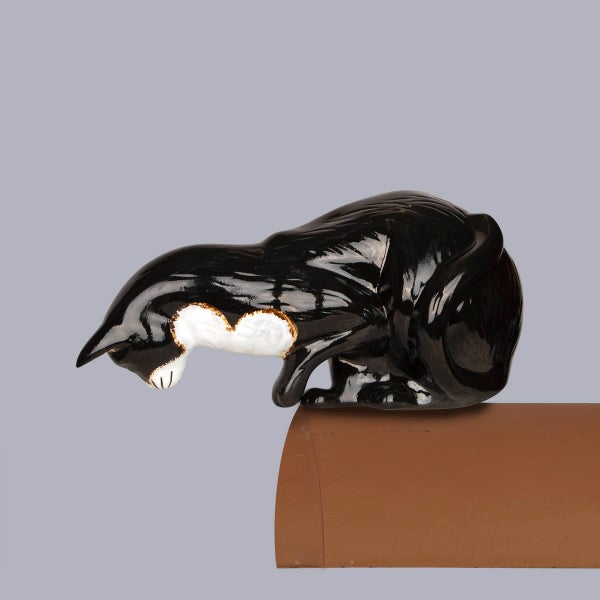 Firstschmuck Katze aus schwarz-weißer glasierter Keramik auf einem Firstziegel.