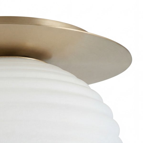 Detailansicht einer Deckenleuchte mit weißem, geriffeltem Glas und einer goldfarbenen Halterung aus Metall.