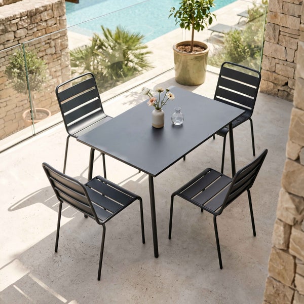 Gartenmöbel-Set aus Metall mit rechteckigem Tisch und vier Stühlen mit Lattendesign auf einer Terrasse mit Steinwand und Poolblick.