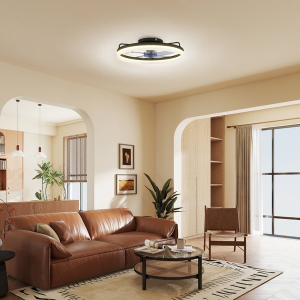 Moderne LED-Deckenleuchte mit integriertem Ventilator in einem hellen Wohnzimmer mit braunem Ledersofa, Holzmöbeln und Zimmerpflanzen.
