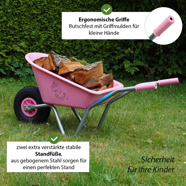 Rosafarbene Kinderschubkarre mit Holz auf einer Wiese, mit ergonomischen Griffen und verstärkten Standfüßen für Stabilität.