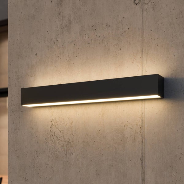 Moderne, rechteckige LED-Wandleuchte in Schwarz an einer Betonwand mit Lichtschein nach oben und unten.