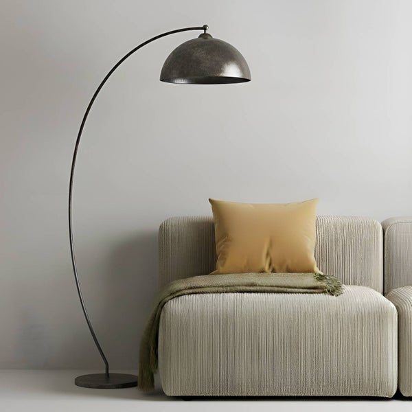 Bogenlampe aus Metall neben einem Sofa mit Kissen und Decke