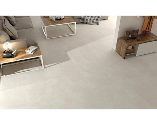 Helles Wohnzimmer mit Bodenfliesen, Sofa, Tisch und Kommode.