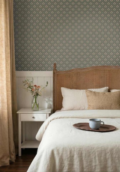 Helles Schlafzimmer mit floraler Tapete, Bett mit Rattan-Kopfteil, weißem Nachttisch und Wandpaneelen.