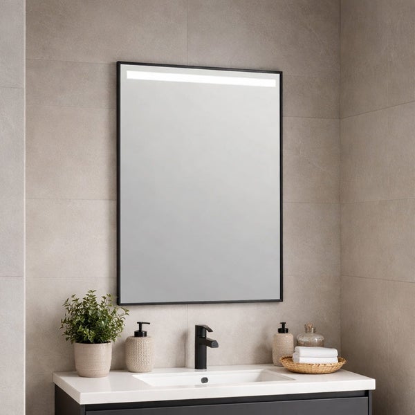 Rechteckiger Badezimmerspiegel mit schwarzem Rahmen und integriertem LED-Lichtstreifen oben, montiert in einem modernen Bad über einem Waschtisch.