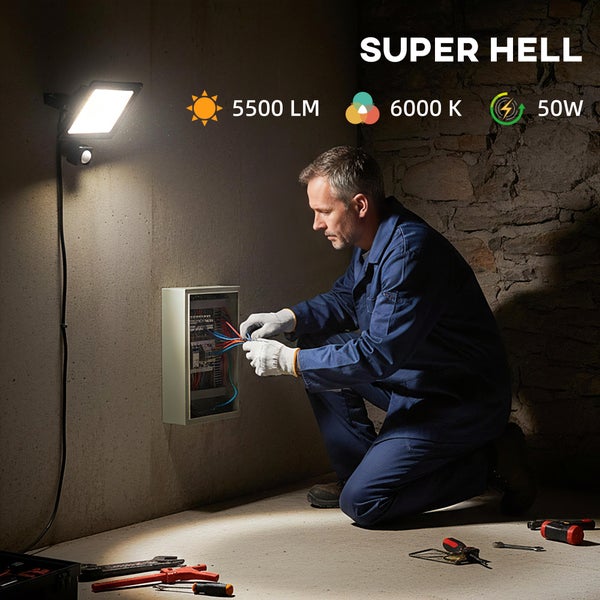 Elektriker arbeitet an einem Verteilerkasten, beleuchtet durch einen 50 Watt LED-Strahler mit Bewegungsmelder, 5500 Lumen und 6000 Kelvin.