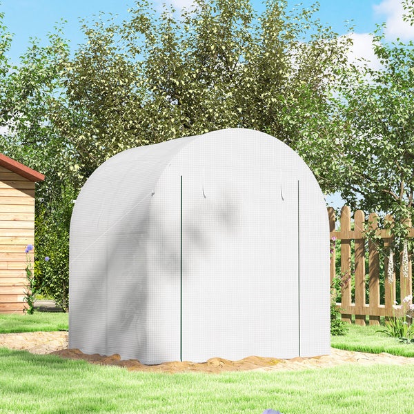 Weißes Foliengewächshaus mit bogenförmigem Dach in einem hellen Garten mit Holzzaun und Bäumen.