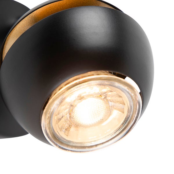 Kugelförmiger LED-Strahler in Schwarz und Gold mit eingeschaltetem Leuchtmittel.