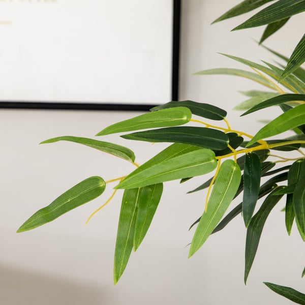 Detailaufnahme einer künstlichen Bambuspflanze mit grünen Blättern und gelben Stielen.