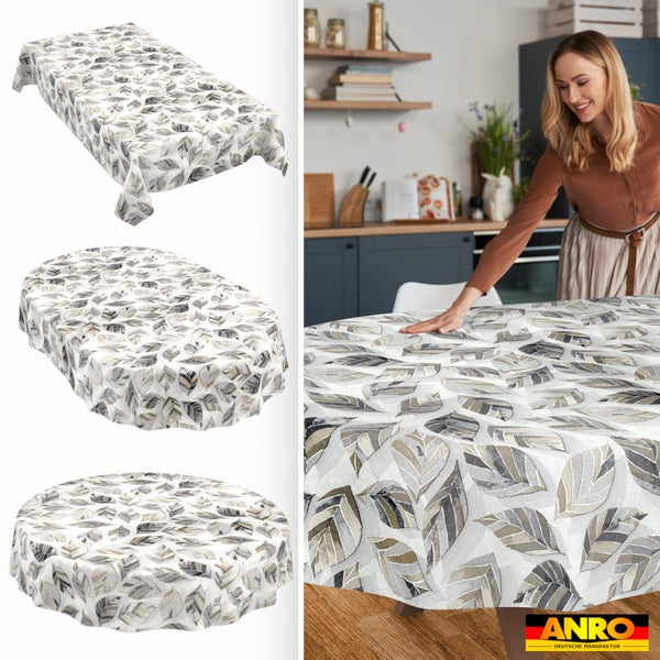 Tischdecke mit Blattmuster in rechteckiger, ovaler und runder Form, Frau glättet Decke in heller, aufgeräumter Küche. ANRO Deutsche Manufaktur Logo.