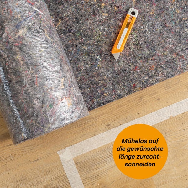 Malervlies wird mit einem Cuttermesser auf einem Holzboden auf die gewünschte Länge zugeschnitten.