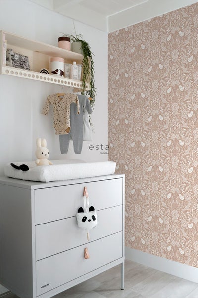 Hell eingerichtetes Babyzimmer mit Kommode, Wandregal und einer Vliestapete mit floralem Muster und Vögeln.