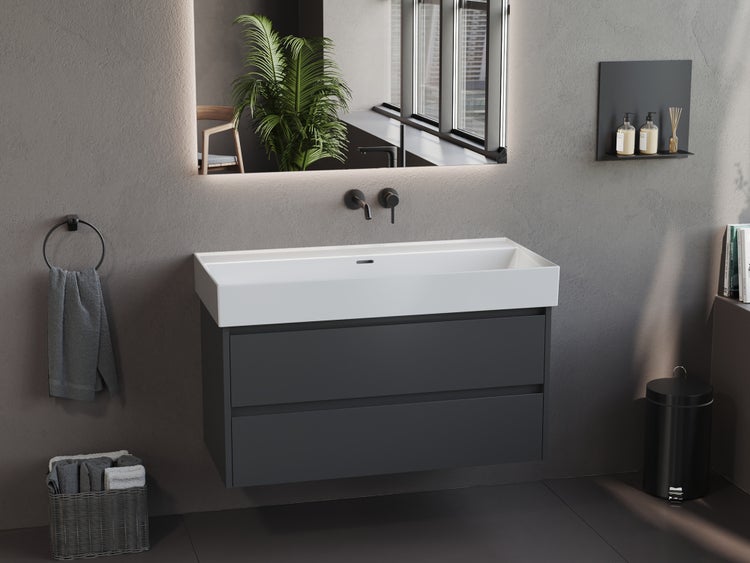 Moderner wandhängender Waschtischunterschrank in Dunkelgrau mit weißem Aufsatzwaschbecken, zwei Schubladen und beleuchtetem Spiegel im Badezimmer.