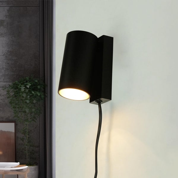 Schwarze Wandleuchte mit Kabel an einer Wand montiert.