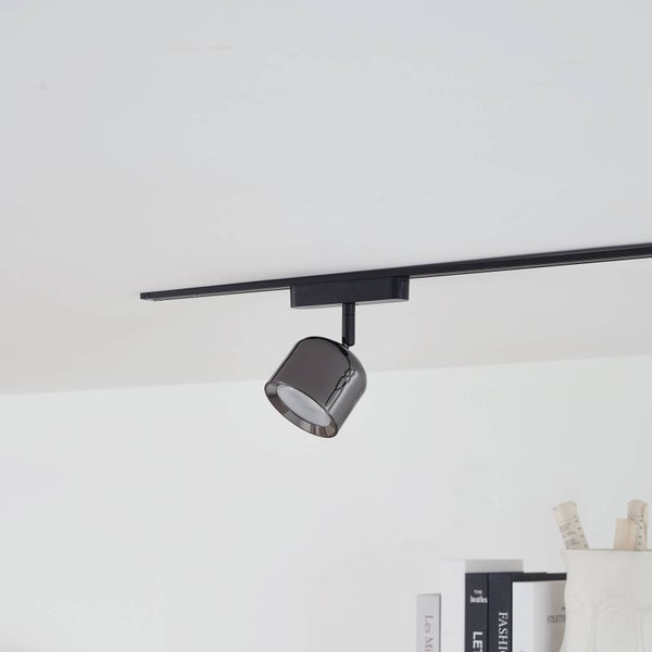 Schwarzes Schienensystem mit einem verstellbaren LED-Strahler in Chrom-Optik an der Decke montiert.