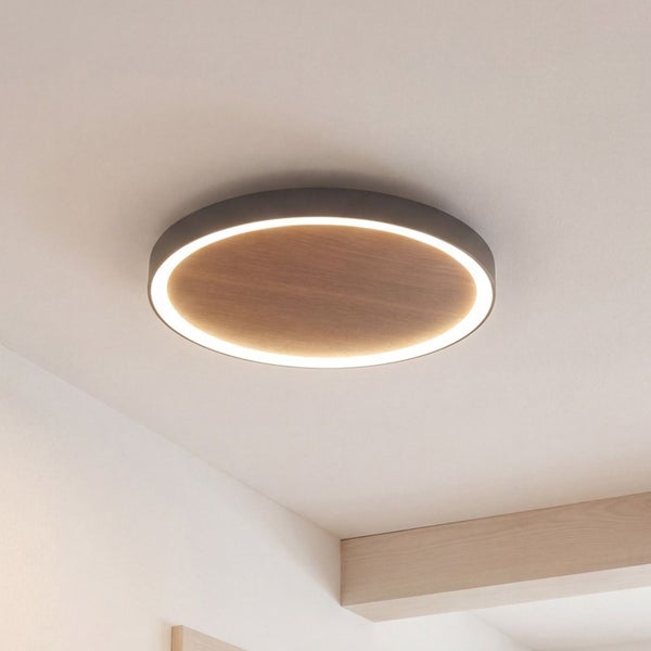 Runde LED Deckenleuchte mit flachem Paneel in Holzoptik und einem umlaufenden Lichtring an der Decke.