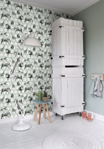 Dekorierter Raum mit Tiermuster-Tapete, Stehlampe, kleinem Beistelltisch und hohem Holzschrank