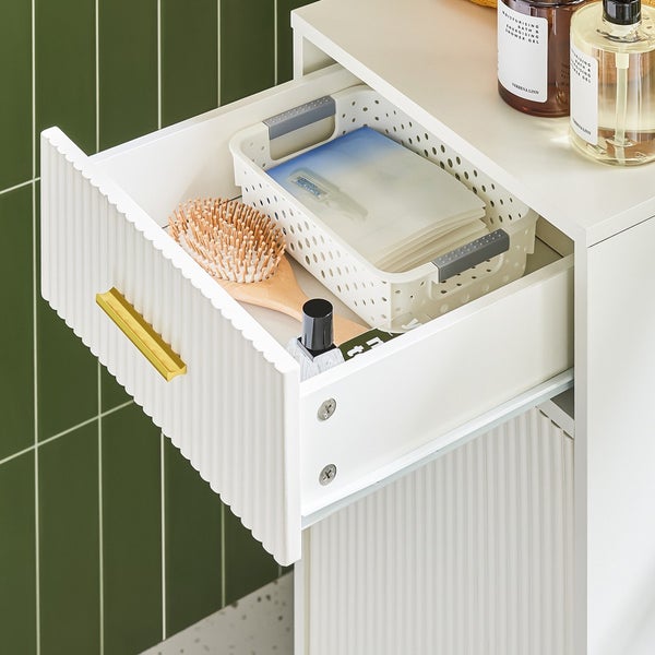 Detailaufnahme eines Badezimmerschranks mit offener Schublade, die Kosmetikartikel und Aufbewahrungskörbe zeigt