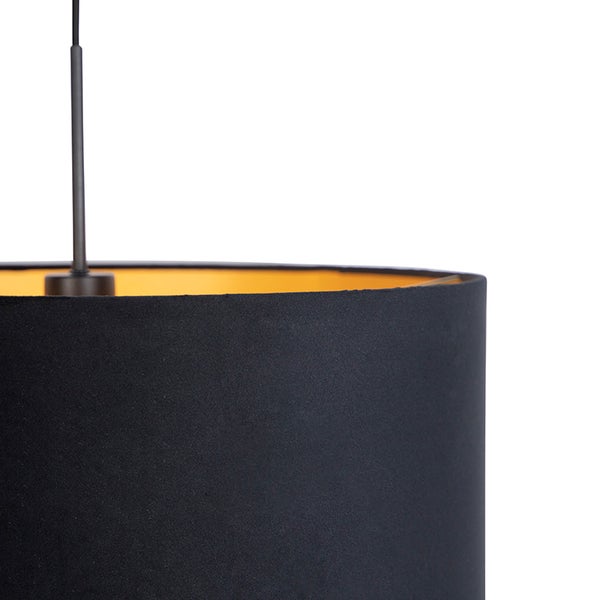 Detailaufnahme einer zylindrischen Pendelleuchte mit schwarzem Stoffschirm und goldener Innenseite.