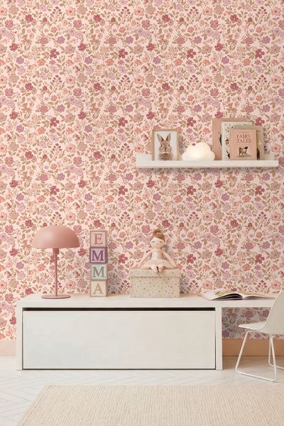 Kinderzimmer mit floral gemusterter Tapete, Schreibtisch, Tischleuchte, Spielzeug und Wandregal.