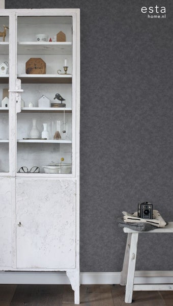 Dekorative Szene mit einem weißen, rustikalen Schrank, grauer Tapete und einer Vintage-Kamera auf einem Hocker.