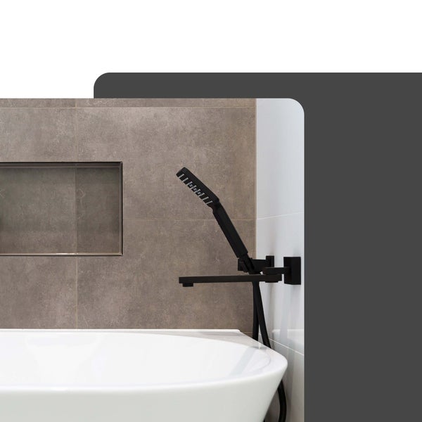Moderne schwarze Wannenarmatur zur Wandmontage mit Handbrause an einer weißen Badewanne vor grau gefliester Wand.