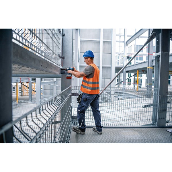 Ein Arbeiter montiert mit einem Akku-Schlagschrauber eine Gitterstruktur.