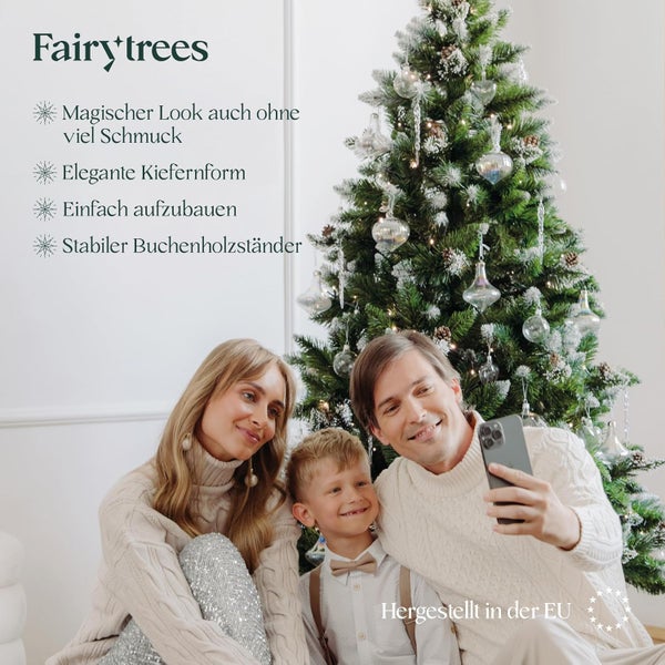 Familie macht Selfie vor einem FairyTrees Weihnachtsbaum mit Buchenholzständer und künstlicher Kiefernform in einem festlichen Wohnzimmer.