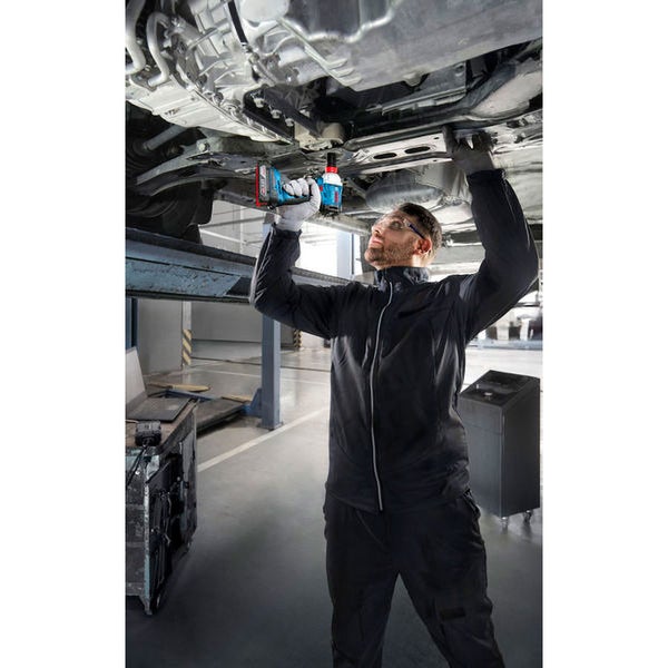 Ein Mechaniker benutzt einen Akku-Schlagschrauber unter einem Auto auf einer Hebebühne.
