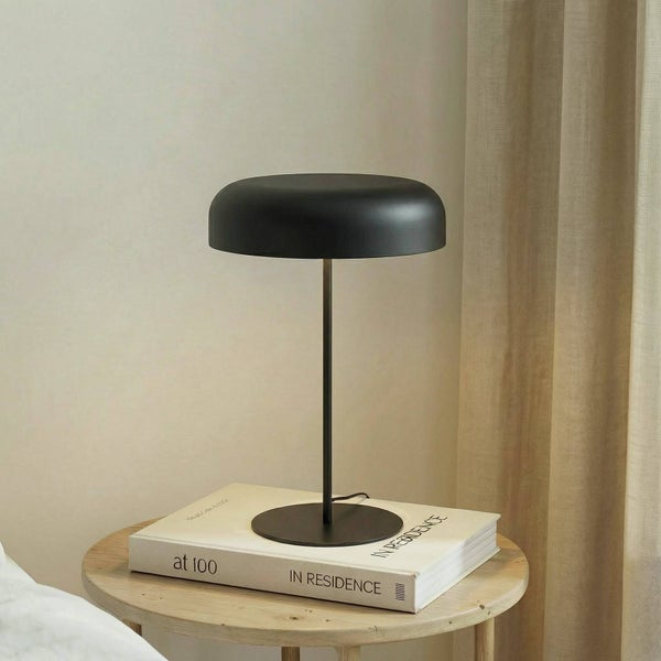 Schwarze Tischleuchte auf einem Buch auf einem Holztisch