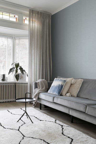 Wohnzimmer mit Sofa, Kissen, Vorhängen, Teppich und Beistelltisch