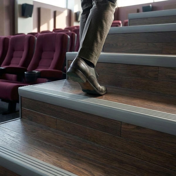 Person geht Treppe mit Holzoptik Stufenprofilen in einem Kino hinauf.