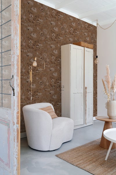 Gemütliches Wohnzimmer mit brauner Blumentapete, Sessel und Kleiderschrank