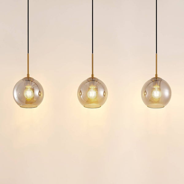 Drei Pendelleuchten mit kugelförmigen Glasschirmen und Metallfassungen an schwarzen Kabeln.