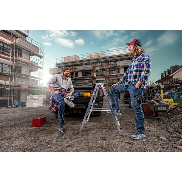 Zwei Handwerker in Arbeitskleidung auf einer Baustelle neben einem Pritschenwagen und einer Aluminium Trittleiter.
