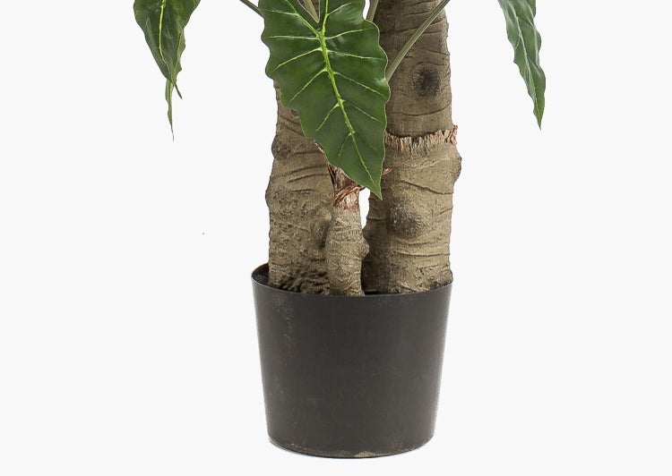 Künstlicher Pflanzenstamm in einem dunkelgrünen Kunststofftopf mit Substrat.