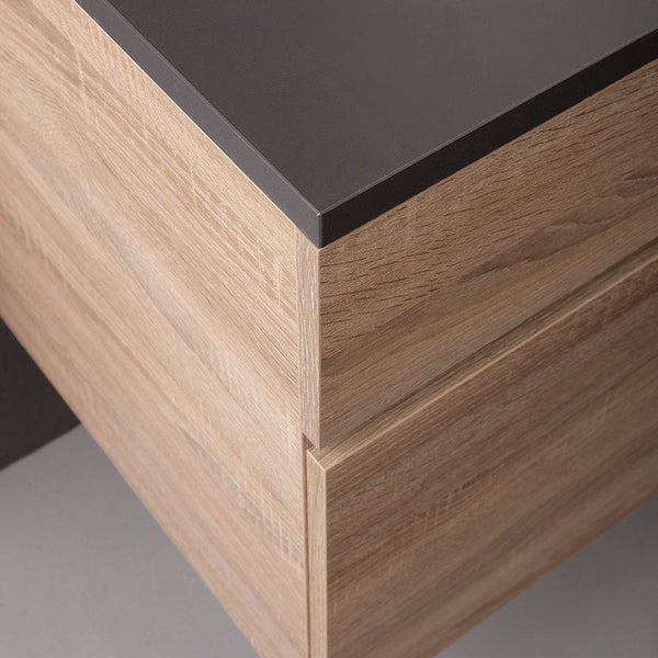 Detailansicht eines Badezimmermöbels mit Holzoptik Oberfläche und einer dunklen Platte.