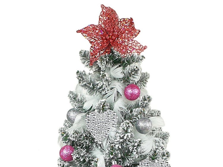 Künstlicher Weihnachtsbaum mit künstlichem Schnee und dekorativen Anhängern wie Weihnachtskugeln und Blumenstern als Baumspitze.