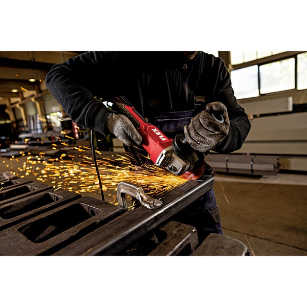 Handwerker mit Arbeitshandschuhen benutzt einen Winkelschleifer der Marke Flex, um ein Metallstück in einer Werkstatt zu bearbeiten.