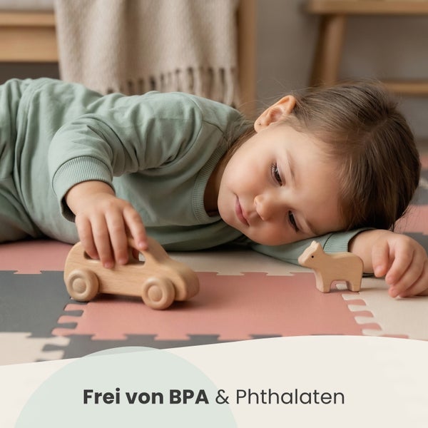 Kleinkind spielt mit Holzspielzeug auf einer Puzzlematte, frei von Bisphenol A und Phthalaten.