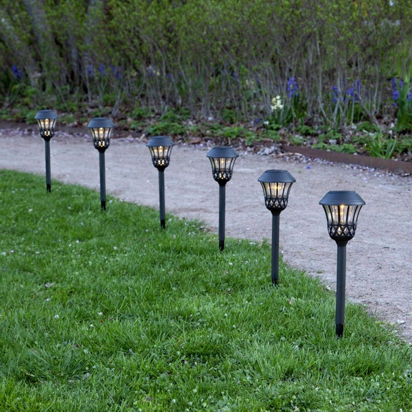 Dekorative Szene mit Papiersternen, Stuhl, Rahmen und Kerzen für eine festliche Atmosphäre.