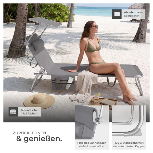 Graue Sonnenliege mit verstellbarem Sonnendach, abnehmbarem Kopfpolster, Seitentasche und rutschfesten Kappen auf einem Strand.
