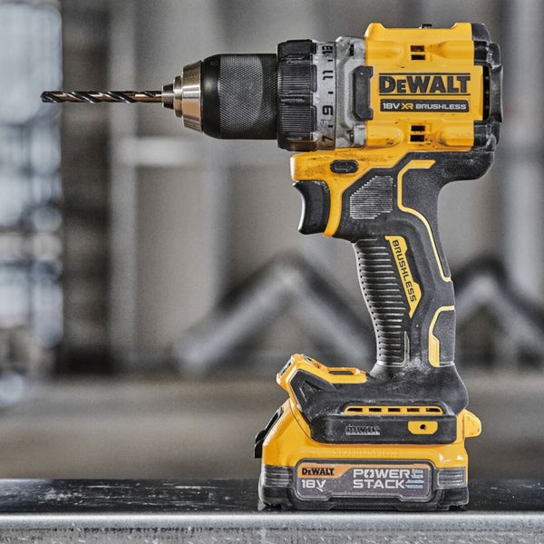 DeWalt Akku-Bohrschrauber 18 Volt XR Brushless mit Powerstack Akku und Metallbohrer auf einer Metallschiene.