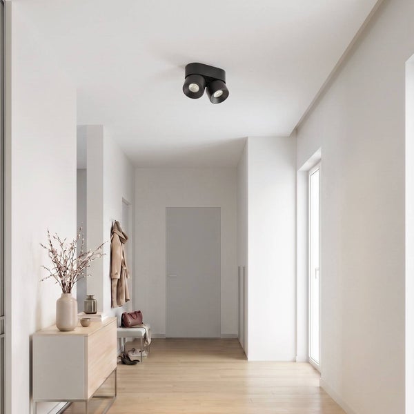 Moderne zweiflammige Deckenleuchte in einem hellen Flur mit Holzboden und minimalistischer Einrichtung.